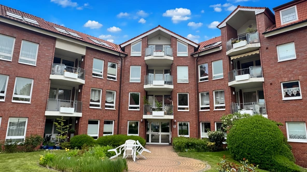 Mehrfamilienhaus aus rotem Backstein mit begrüntem Innenhof und Balkonen